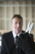 Hand holding a plier with gagged businessman looking at it