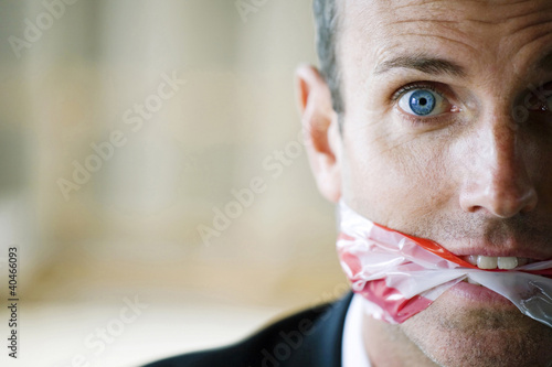 Foto: Terrified looking man with gagged mouth Terrified looking man with gagged mouth