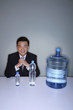 Businessman smiling at the camera with three water bottles on the table