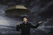 Businessman checking on the weather while holding an umbrella