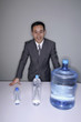 Businessman smiling at the camera with three water bottles on the table