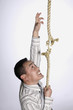 Businessman climbing a tearing rope