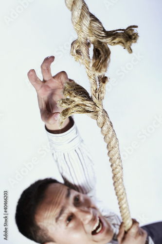 Photo: Businessman climbing a tearing rope Businessman climbing a tearing rope