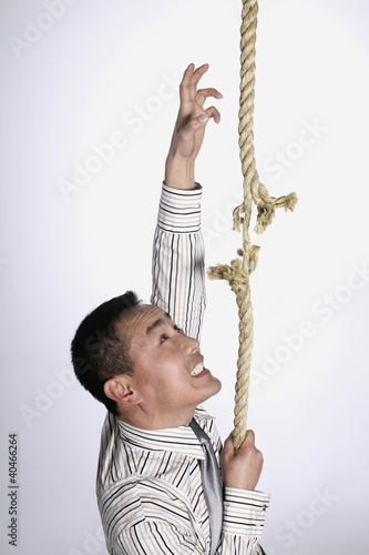 Photo: Businessman climbing a tearing rope Businessman climbing a tearing rope