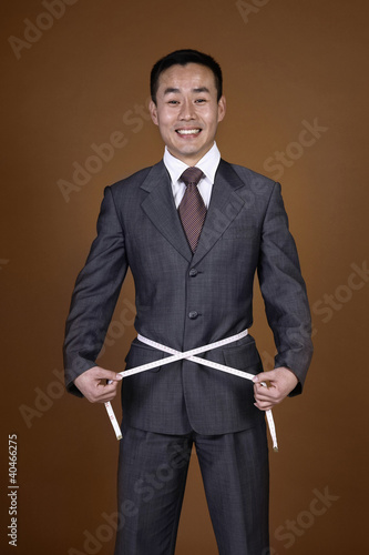 Photo: Businessman with measuring tape around his waist Businessman with measuring tape around his waist