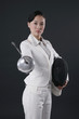 Businesswoman holding fencing mask and thrusting a fencing foil