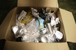 Cardboard box filled with plastic bottles, tin cans, papers, rope and a globe