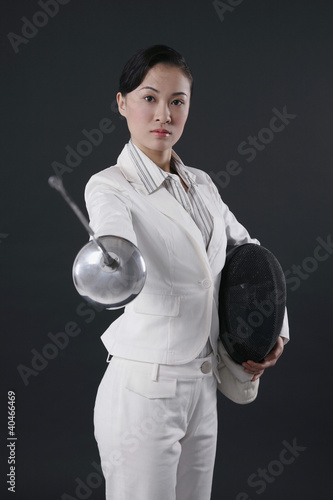 Photo: Businesswoman holding fencing mask and thrusting a fencing foil Businesswoman holding fencing mask and thrusting a fencing foil