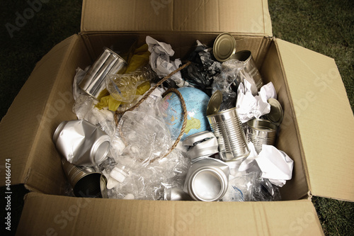 Photo: Cardboard box filled with plastic bottles, tin cans, papers, rope and a globe Cardboard box filled with plastic bottles, tin cans, papers, rope and a globe