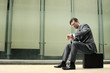 Businessman checking the time on his watch while sitting on bag