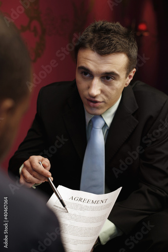 Foto: Businessman explaining document terms with another businessman Businessman explaining document terms with another businessman