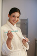 Woman in bathrobe holding toothpaste and toothbrush