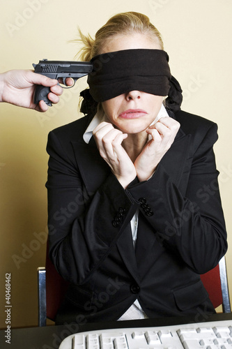 Photo: Gun being pointed at a blindfolded businesswoman Gun being pointed at a blindfolded businesswoman
