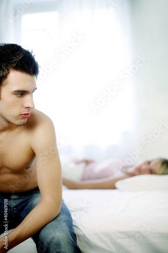 Photo: Man sitting on the bed thinking Man sitting on the bed thinking
