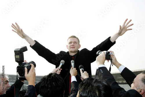 Foto: Businessman calming down reporters at a press conference Businessman calming down reporters at a press conference
