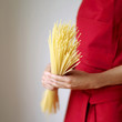 Side view of a lady in red apron holding some spaghetti