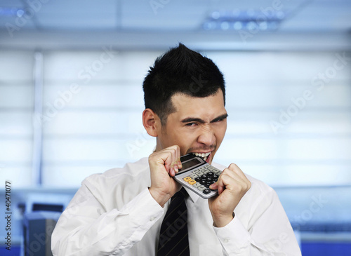 Foto: Businessman biting on a calculator Businessman biting on a calculator