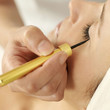 Hand applying liquid eyeliner on woman's eyelid