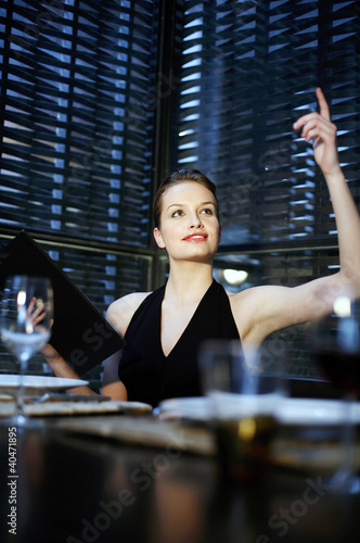 Photo: Woman raising her hand to order her food in a restaurant Woman raising her hand to order her food in a restaurant