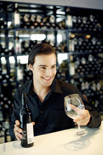 Photo: Man holding a bottle of wine and a wine glass Man holding a bottle of wine and a wine glass
