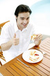 Photo: Man showing thumbs up while enjoying his breakfast Man showing thumbs up while enjoying his breakfast