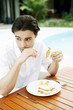 Photo: Man enjoying his breakfast by the pool side Man enjoying his breakfast by the pool side