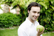 Photo: Man holding a green apple while smiling at the camera Man holding a green apple while smiling at the camera