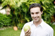 Photo: Man holding a green apple while smiling at the camera Man holding a green apple while smiling at the camera
