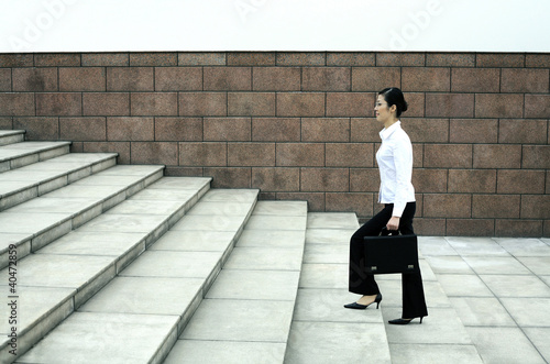 Photo: Businesswoman with briefcase walking up the stairs Businesswoman with briefcase walking up the stairs