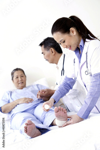 Foto: Doctor bandaging patient's ankle Doctor bandaging patient's ankle