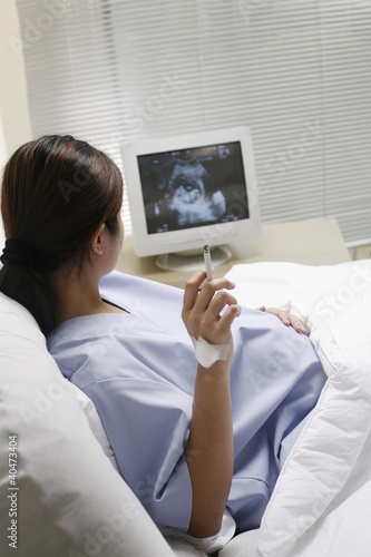 Photo: Pregnant woman lying on the bed smoking Pregnant woman lying on the bed smoking
