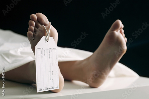 Photo: Toe tag hanging on woman lying on table in morgue Toe tag hanging on woman lying on table in morgue