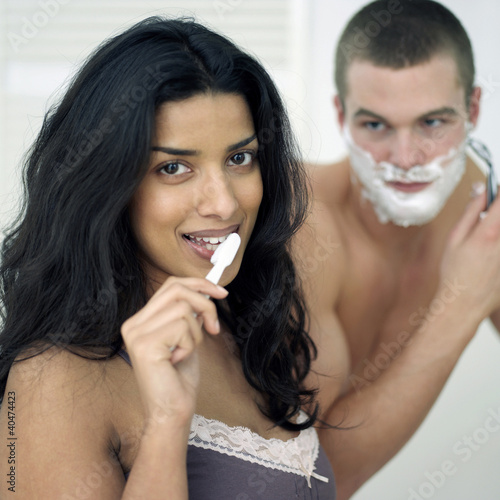 Photo: Man shaving his face while his girlfriend is brushing teeth Man shaving his face while his girlfriend is brushing teeth