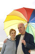 A man having his arms around his wife, holding an umbrella