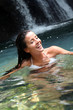 Beautiful woman enjoying bathing near natural waterfall