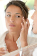 Portrait of beautiful woman applying anti-wrinkles cream