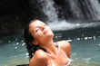Beautiful woman enjoying bathing near natural waterfall