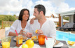 Cheerful couple taking breakfast on the outdoor terrace