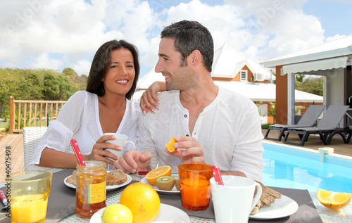 Photo: Cheerful couple taking breakfast on the outdoor terrace Cheerful couple taking breakfast on the outdoor terrace