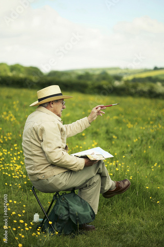 Foto: Senior man sitting on the field drawing Senior man sitting on the field drawing