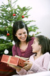 Little girl receiving a Christmas present from her mother