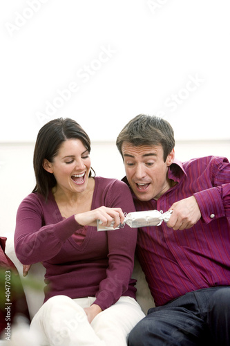 Photo: A couple grabbing a gift excitedly A couple grabbing a gift excitedly