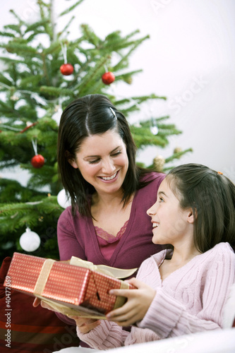 Photo: Little girl receiving a Christmas present from her mother Little girl receiving a Christmas present from her mother
