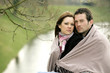 Happy couple wrapped in blanket