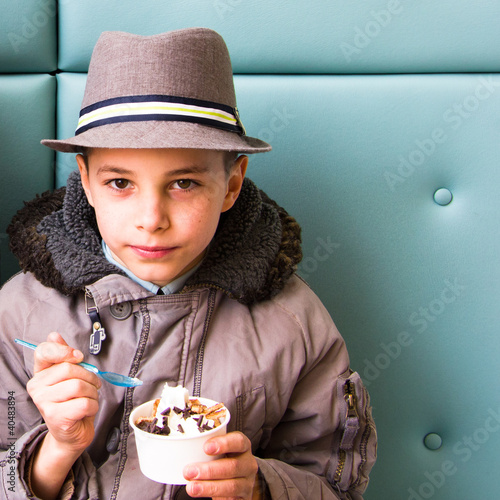 Photo: Cute teenage boy eating ice cream with chocolate topping Cute teenage boy eating ice cream with chocolate topping