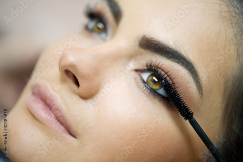 Photo: Woman applying mascara on her long eyelashes Woman applying mascara on her long eyelashes