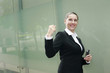 Businesswoman holding cellphone, shaking fist in victory