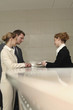 Receptionist passing a letter to businessman and businesswoman