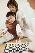 Man and woman playing chess game with boy