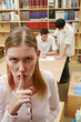 Woman with finger on lips in the library